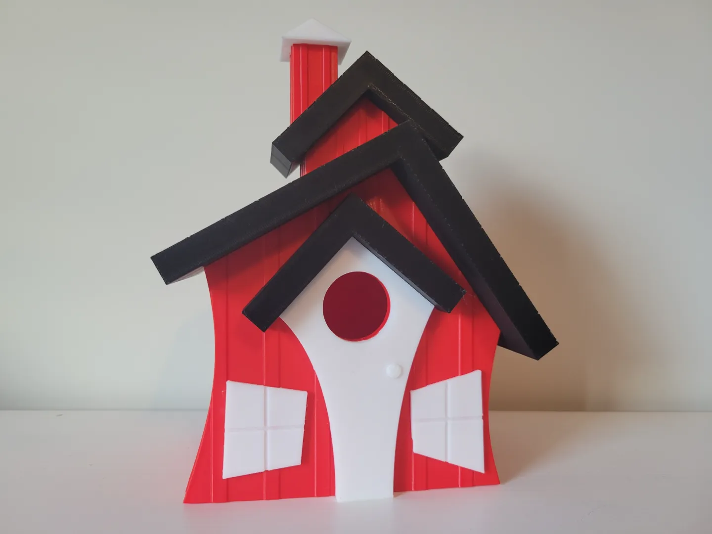 Assembled red, white and black 3D-printed birdhouse with a dark tiled roof