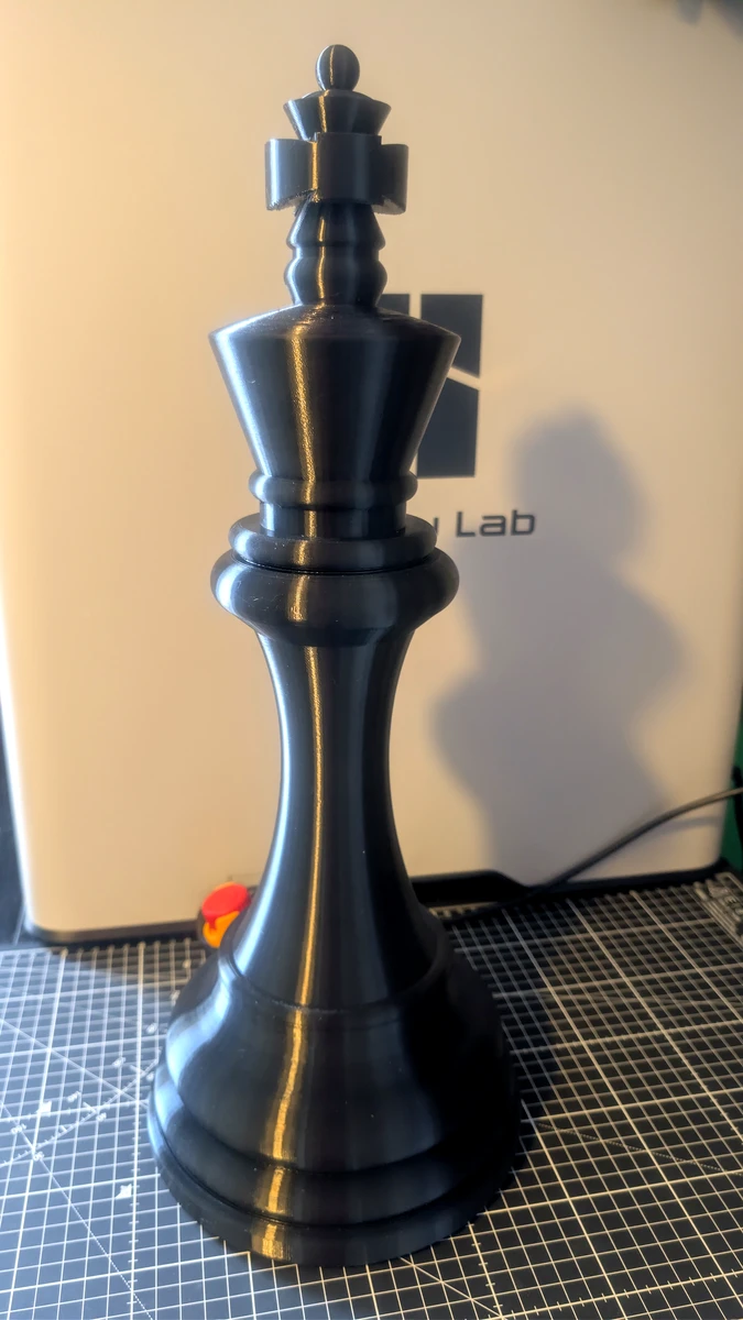Raw black 3D-printed king piece sitting on a workshop cutting mat