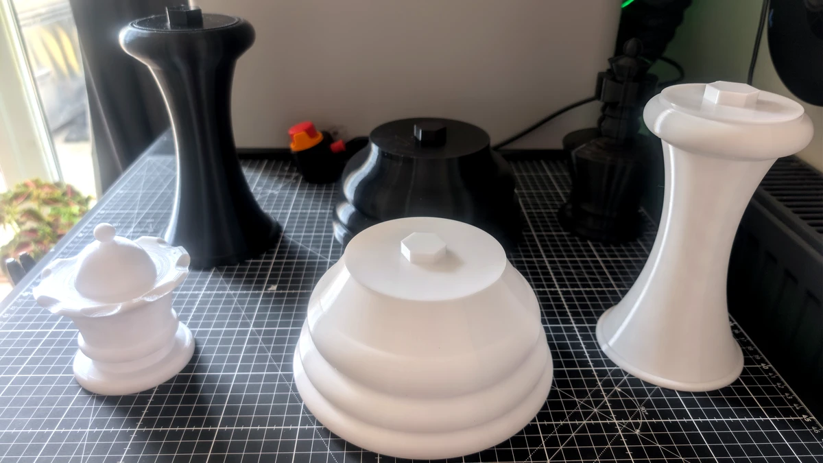 Disassembled white and black printed parts showing bases, bodies, joints, and crowns sitting on a cutting mat